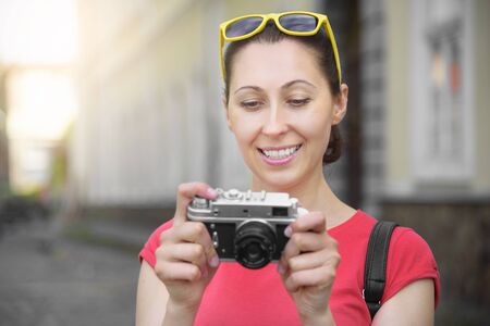 Tourist girl using camera to take photograph on travel. Focus on camera.の写真素材
