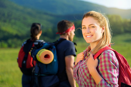 Friends tourists in nature. Active hikers hiking enjoying view looking at mountain forest landscape.