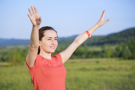 Happy traveler girl with raised up hands enjoying valley view, mountains landscape, happiness emotion, summer holiday conceptの写真素材