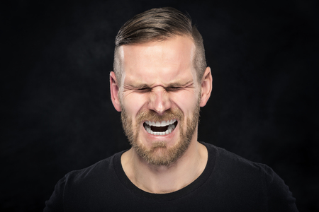Young man screaming on a dark background.の写真素材
