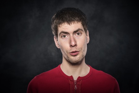 Young man funny face on a dark background.の写真素材