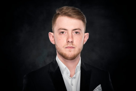 Businessman in suit standing on dark background.