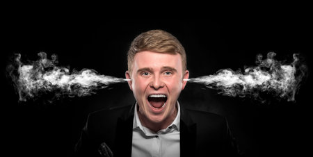 Angry man with smoke or fume coming out from his ears on dark background.の写真素材
