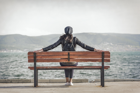 Woman sitting on the bench near the sea.の写真素材