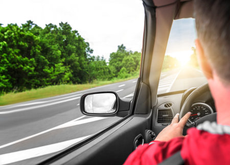 Male driver drives a convertible car on the country road. The view from the cabin, rear view,...