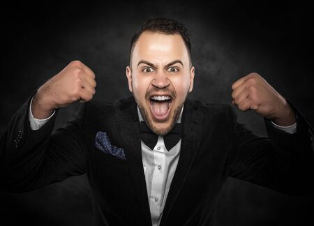 Young man cellebrate on a dark background.の写真素材
