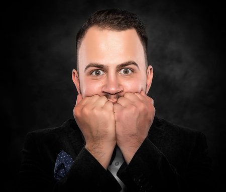Excited or scared young man on a dark background.の写真素材