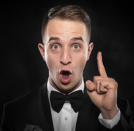 Idea. Young man shows finger up over darck background.の写真素材