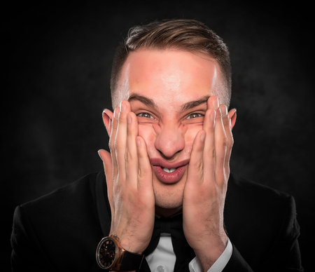 Excited or scared young man on a dark background.