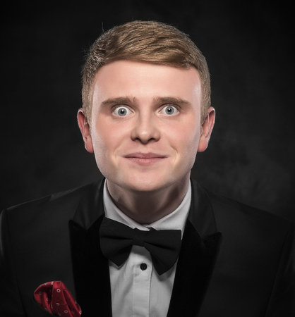 Portrait of surprised man in suit with bow-tie over dark background.の写真素材