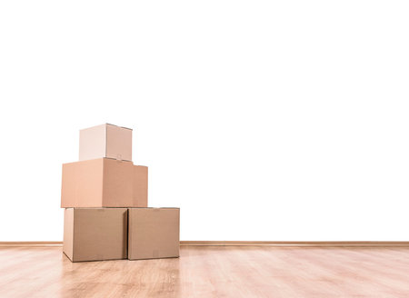 Empty room with a white wall and moving boxes on the floor.