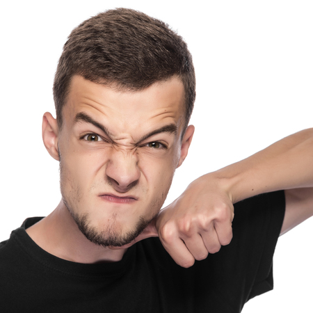 Young man gesturing a cutting motion on her throat over white background.の写真素材