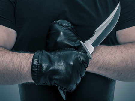 Man with athletic hands holding a military knife. Close-up.