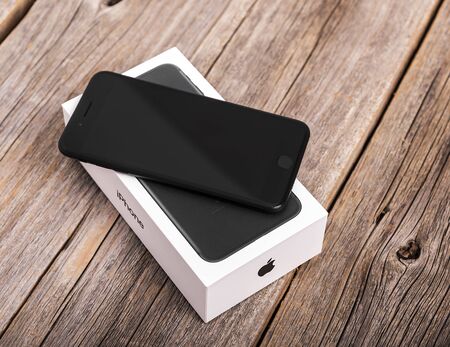 UZHGOROD, UKRAINE - DECEMBER 20, 2016: New black iPhone 7 Plus from the company Apple, and branded packing box, on wooden background.のeditorial素材