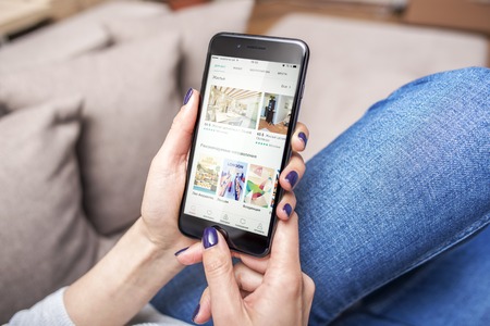 Black iPhone 7 Plus with Airbnb, app for booking apartments and hotels in hands.のeditorial素材