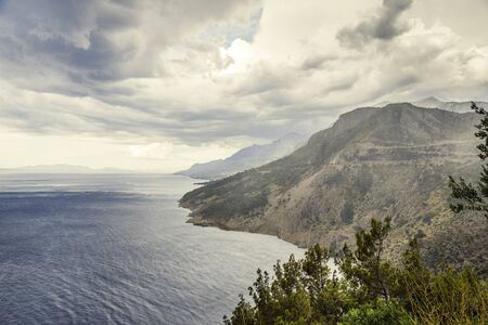 Dark stormy sky, sea waves, mountains.の写真素材