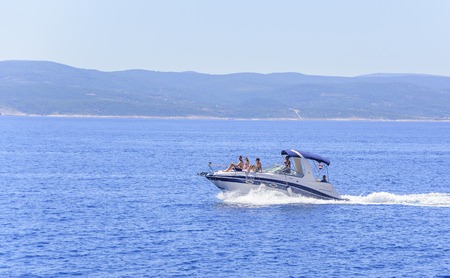 The boat with the resting people is moving quickly on the sea waves.のeditorial素材