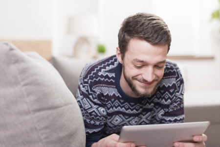 Young smiling man with a tablet computer in hand at home.の写真素材
