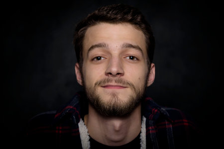 Portrait of a young man with a beard on a dark background.