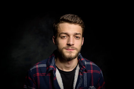 Portrait of a young man with a beard on a dark background.