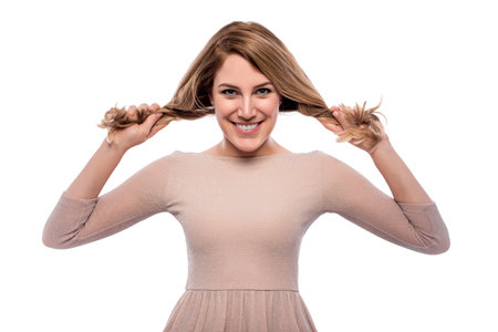 A young woman is pulling herself at the braids on a white background.