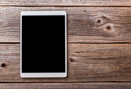 White tablet pc on old wood table background.