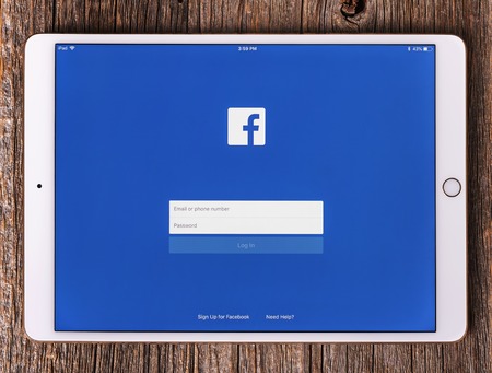 Ipad pro with social network Facebook on the screen, on a wooden table.のeditorial素材