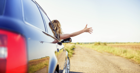An attractive woman in a car holds a car key in her hand.の写真素材