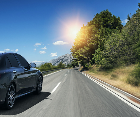 Black car rushing along a high-speed highway in the sun.の写真素材