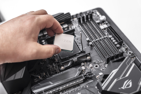 Processor Ryzen 7 2700X in hand against the background of a computer motherboard.のeditorial素材