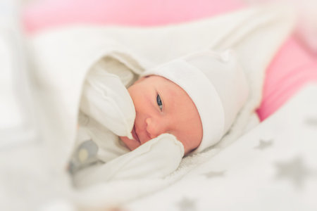 Smiling sleepy baby close-up in a baby cot.