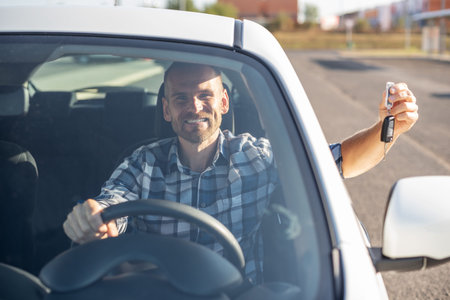 A man in a white car shows a key.