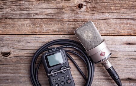 Large diaphragm condenser studio microphone Neumann tlm 103 and Zoom H5 recorder on a wooden background.のeditorial素材