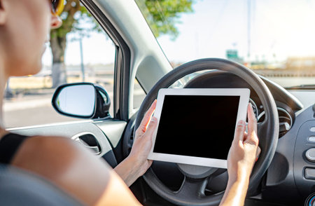 Young woman holding tablet computer sitting in the car.
