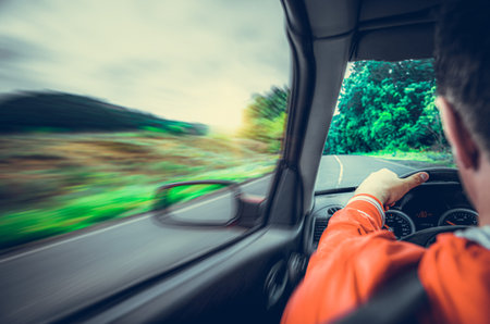 A man drives a car on a suburban highway.