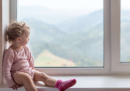 Lonely child looks out the window.の写真素材