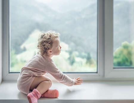 Lonely child looks out the window.の写真素材