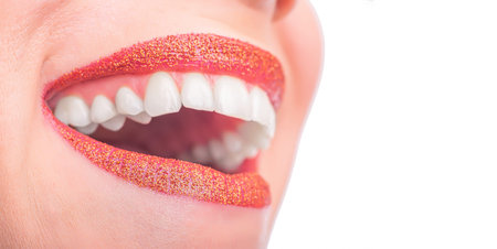 Womans face with red lipstick on the lips and white teeth.