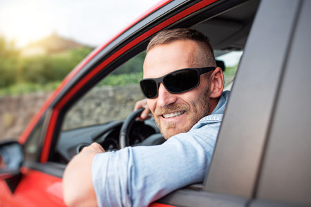 Man with a beard driving a car.