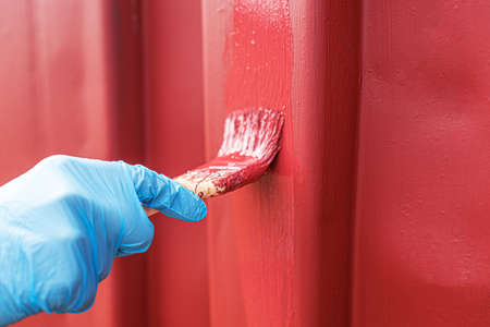 A hand in a glove paints a surface.の写真素材