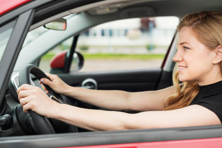 Happy beautiful woman drives a car.