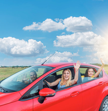 Friends in a red car. Travel freedom concept.