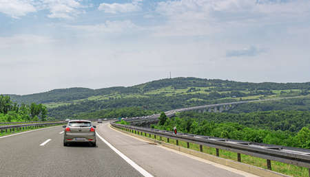 KIA Ceed and other cars drive along the highway with a bridge in Plitvice, Croatia.のeditorial素材
