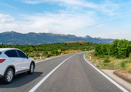 Car is driving along the road. White car on a suburban highway.の写真素材