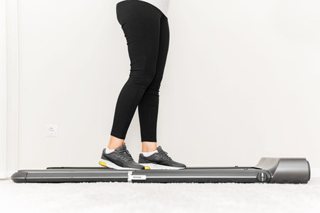 Sporty woman using walking treadmill on white background