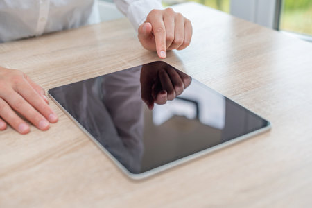 Tablet with a blank screen in the hands on wooden table