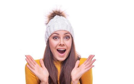 Surprised woman in a sweater and hat posing on a white background.