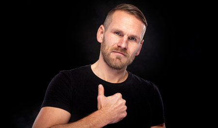Young man with a beard on a black background.