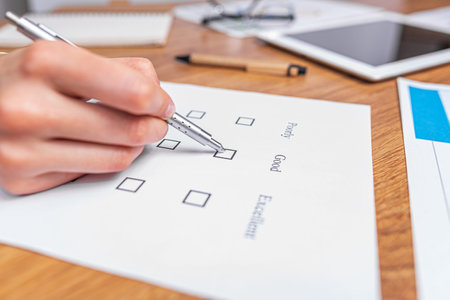 A womans hand fills out a checklist or an exam test giving a mark of good or bad.