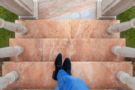 Mens feet on the steps. A man in jeans and black shoes on the marble steps.の写真素材